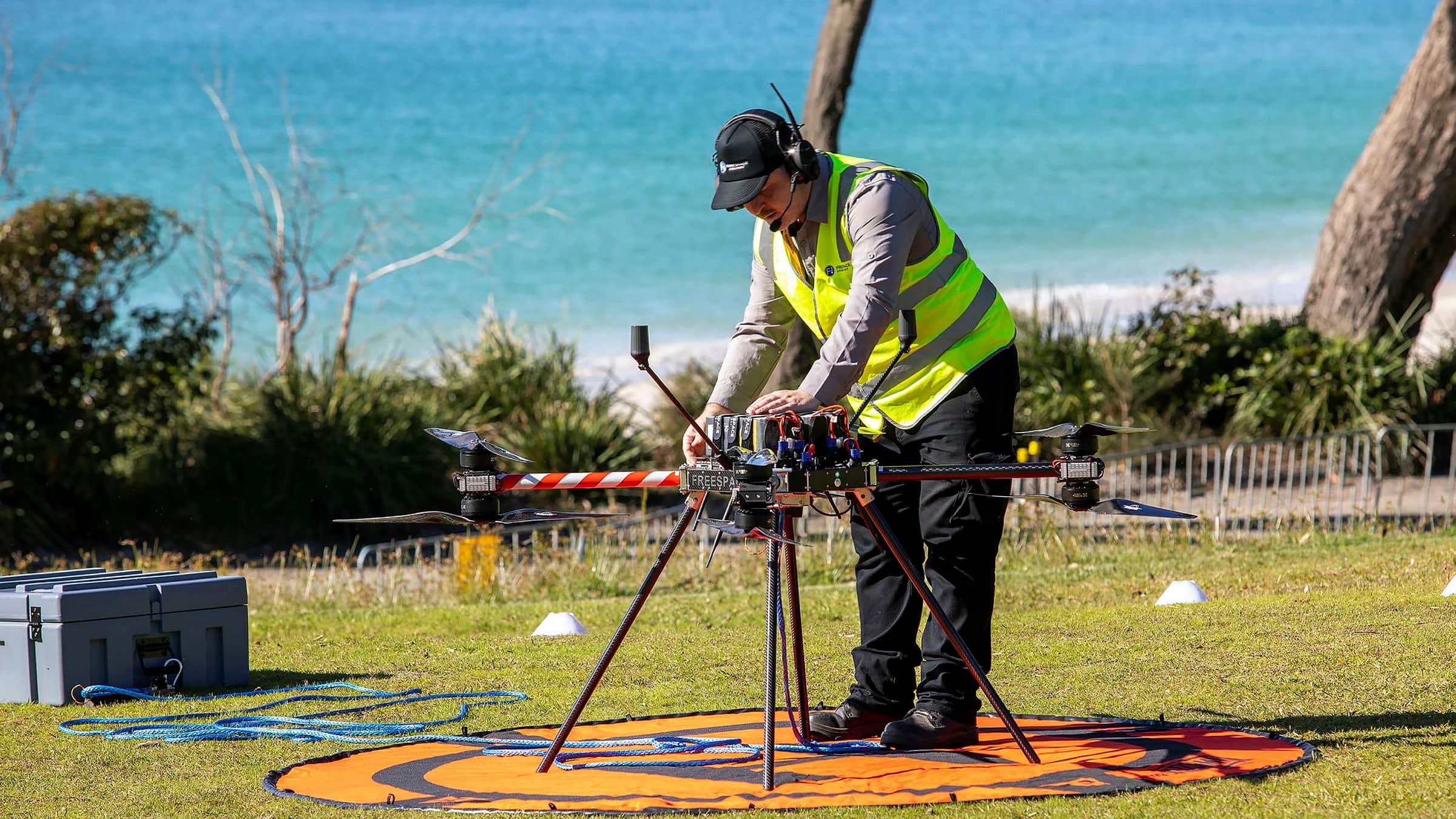 A technician in hi-vis preparing a Callisto on a landing pad above a beach