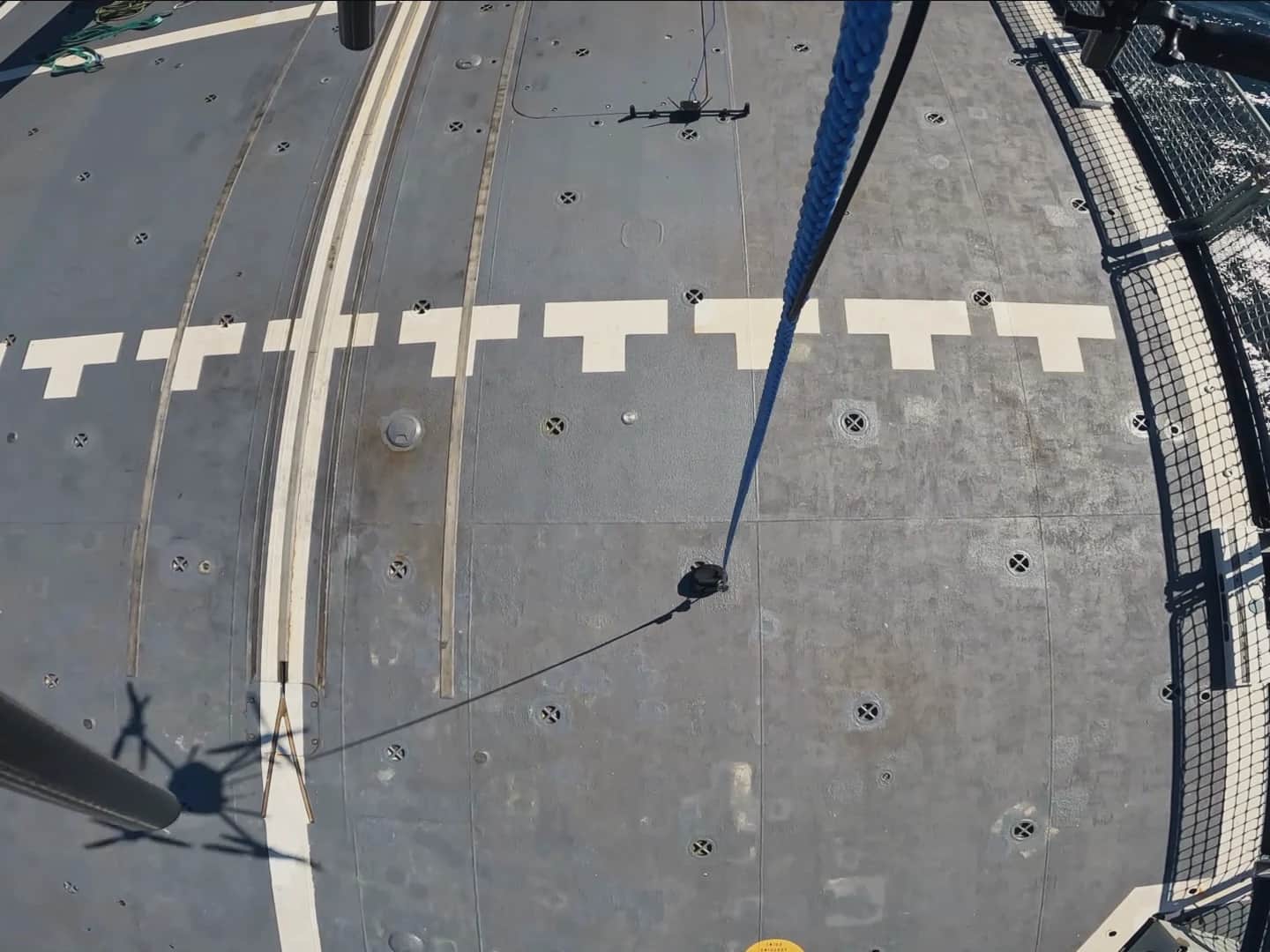 Looking down from a Callisto at a naval vessel's flight deck, its tether running to the deck