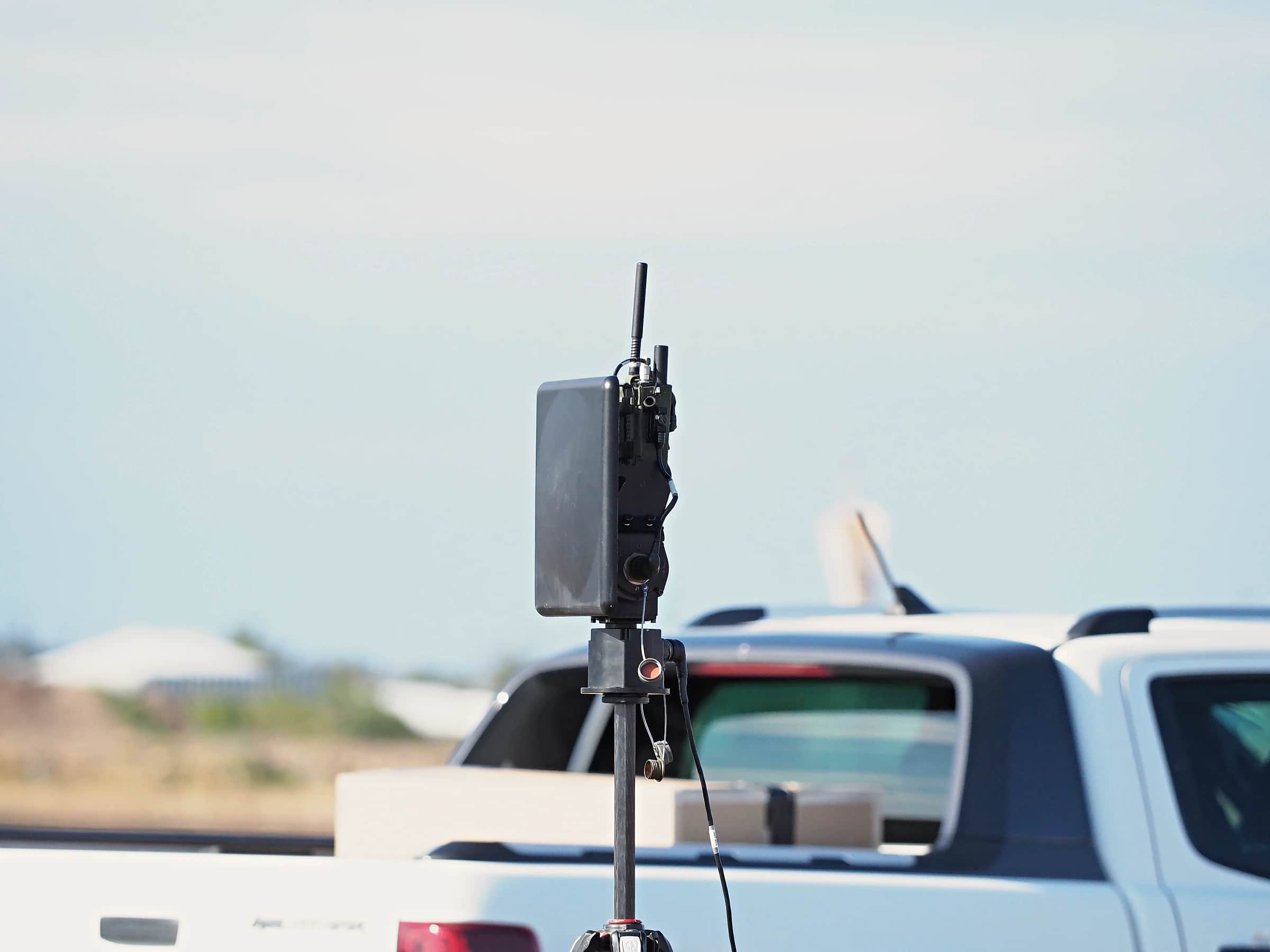 A communications relay mast on a tripod beside a ute at an airfield