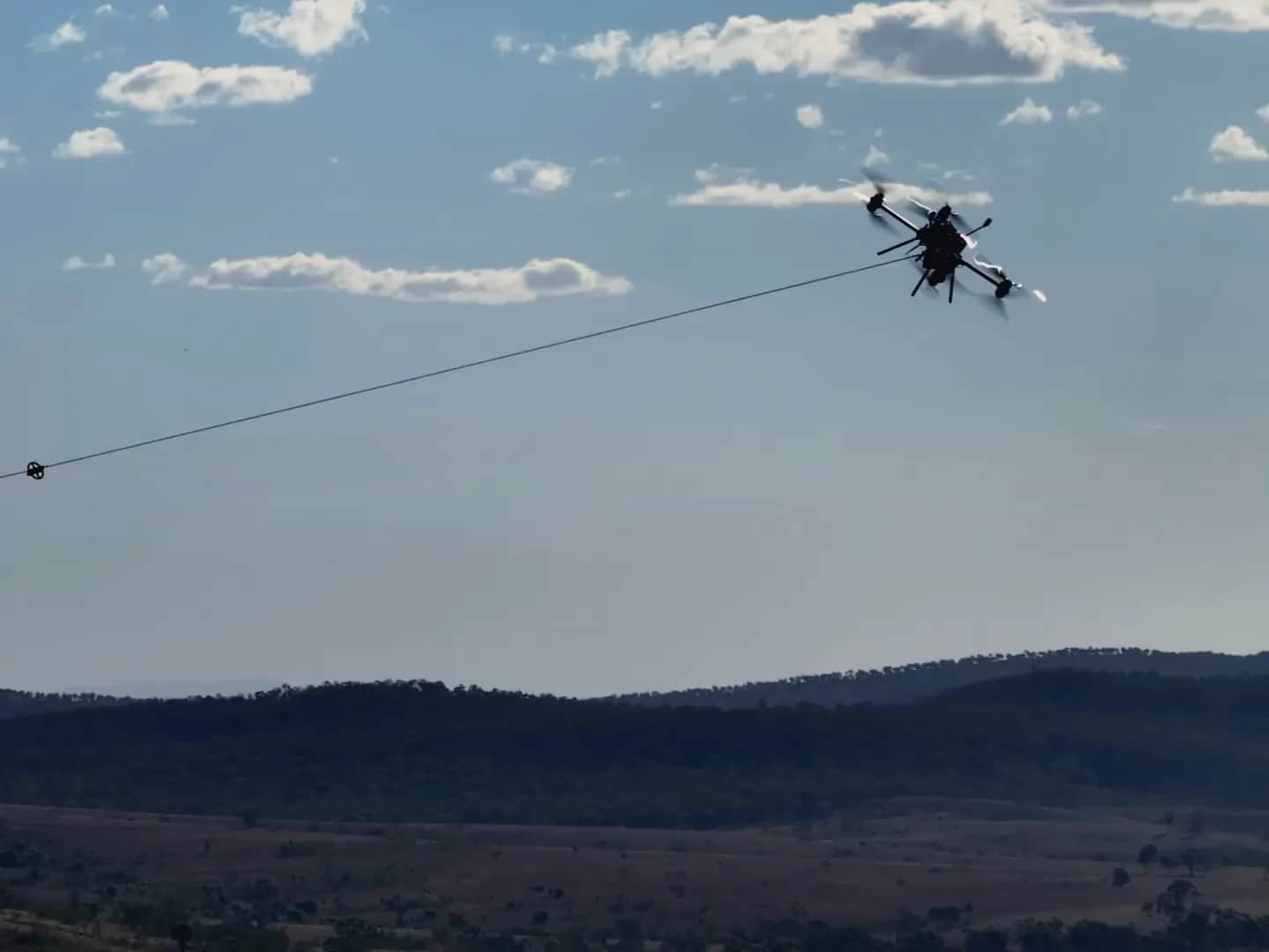 A Callisto pulling a pilot line across a valley, hills behind