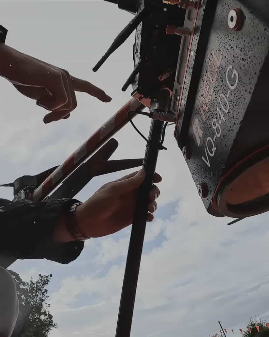 An operator's hands fitting a RIEGL LiDAR beneath a Callisto, the aircraft seen from below